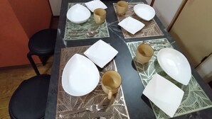 Una mesa de comedor dispuesta con platos blancos, copas doradas y una cuchara de plata.