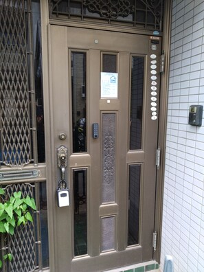 A brown door with a keypad lock, a small sign above the door, and a window with a decorative pattern. - Modern Japanese-style house‼️ Lowest price ‼️ 10 min. from Tokyo/Ikebukuro / Max 5 guests / Families & long-term stays welcome / Backpackers / Relaxation   (Kita City)