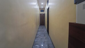 A narrow hallway with a marble floor, beige walls, and a wooden door at the end. - AAI OM Residency (Mumbai)