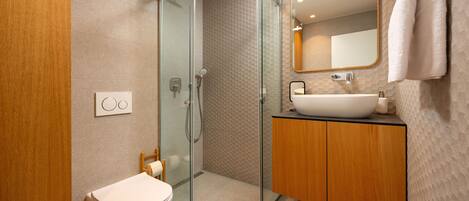 A modern bathroom with a glass-enclosed shower, a wooden vanity, and a large mirror.