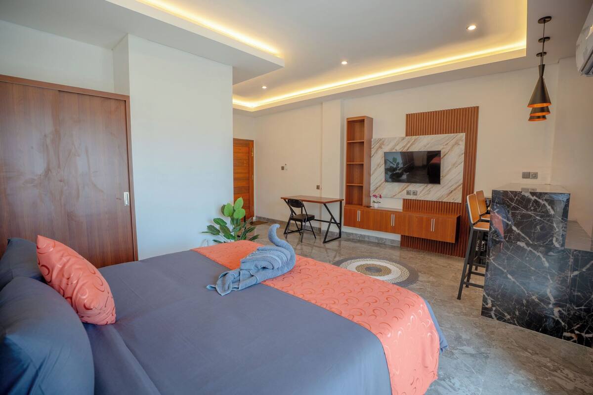 Une chambre à coucher moderne, équipée d’un lit, d’un bureau et d’un téléviseur fixé au mur.
