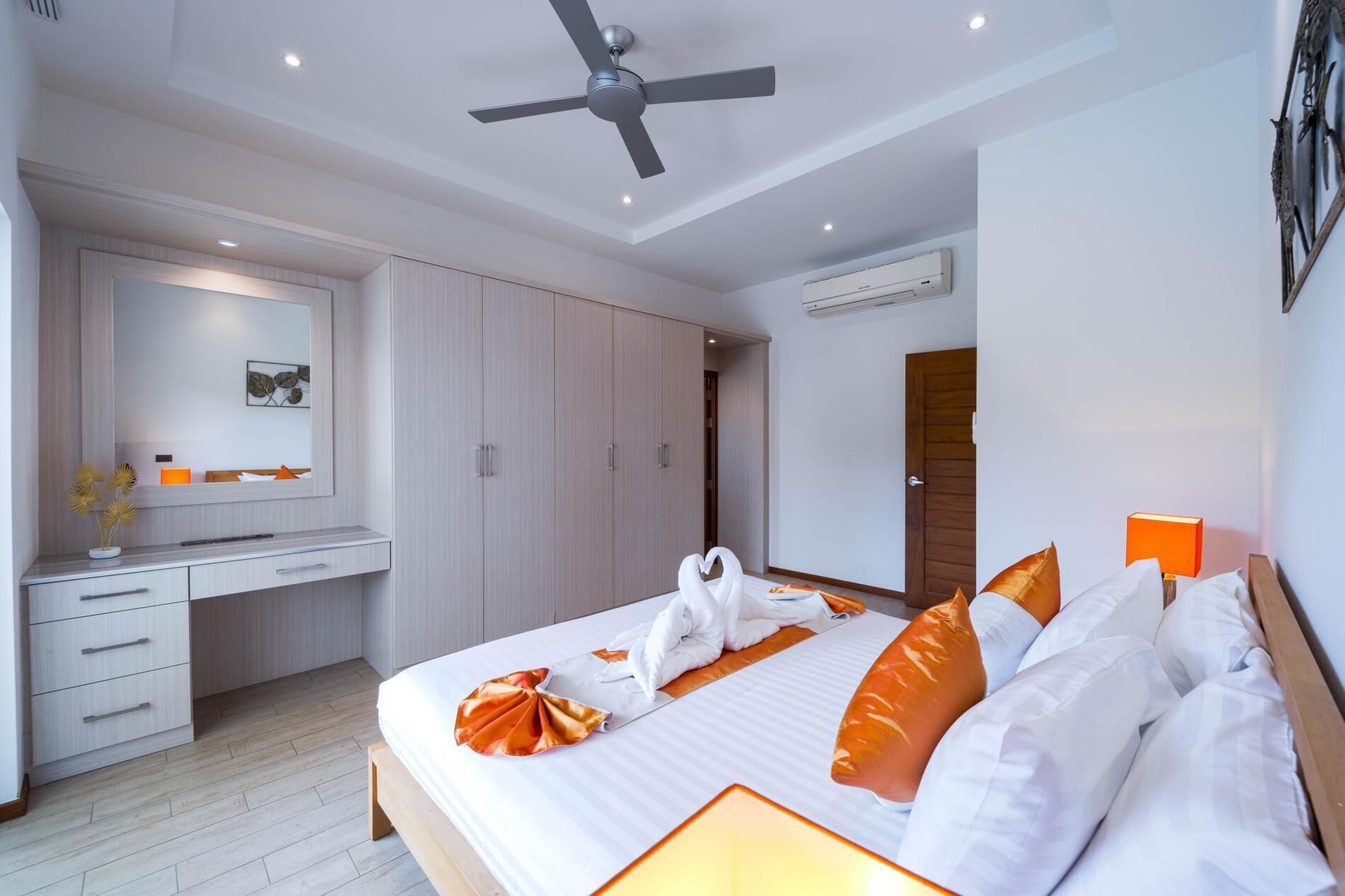 Ein modernes Hotelzimmer mit Bett, Schreibtisch und Deckenventilator.
