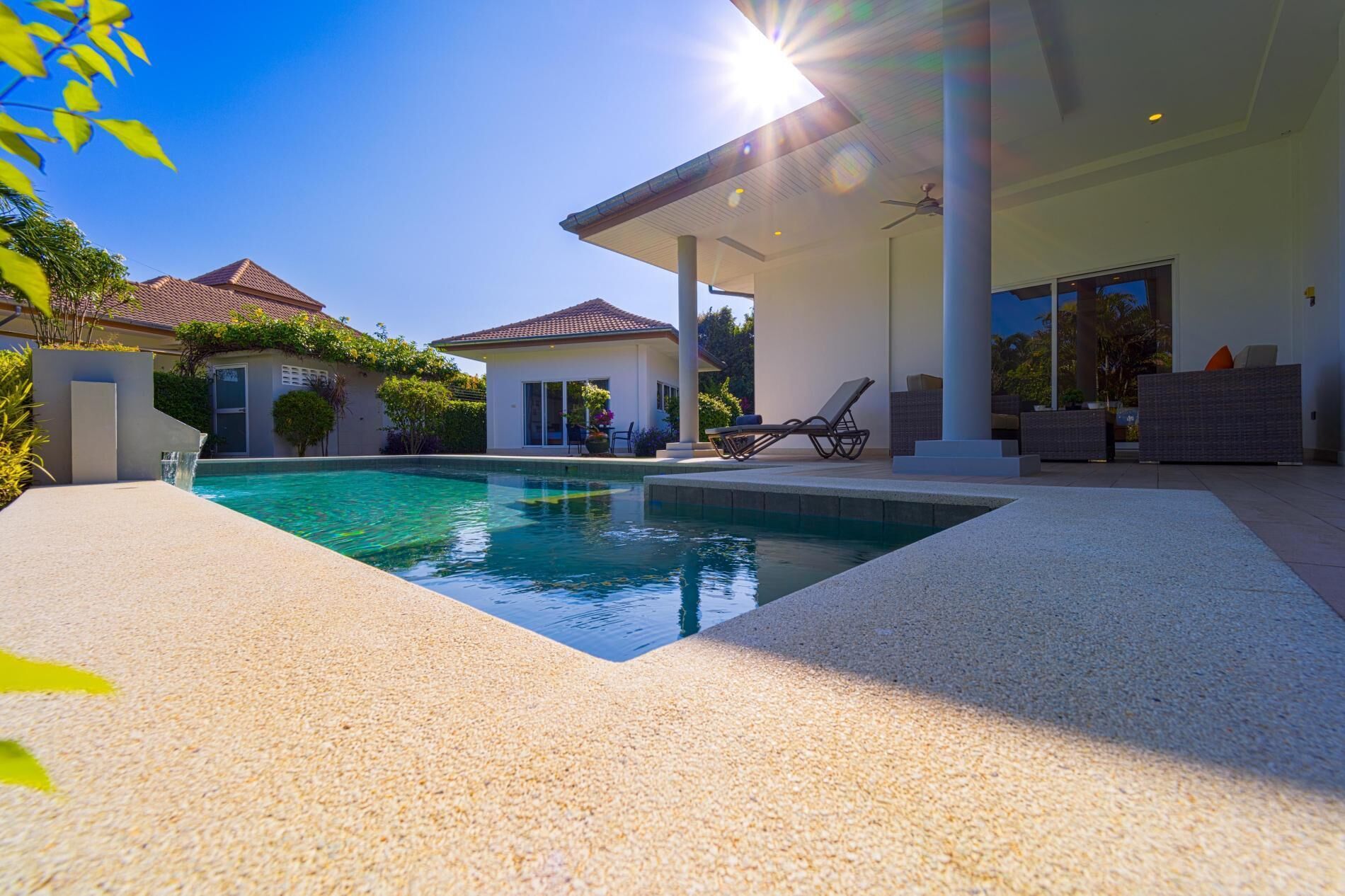 A modern house with a swimming pool, covered patio, and outdoor furniture.