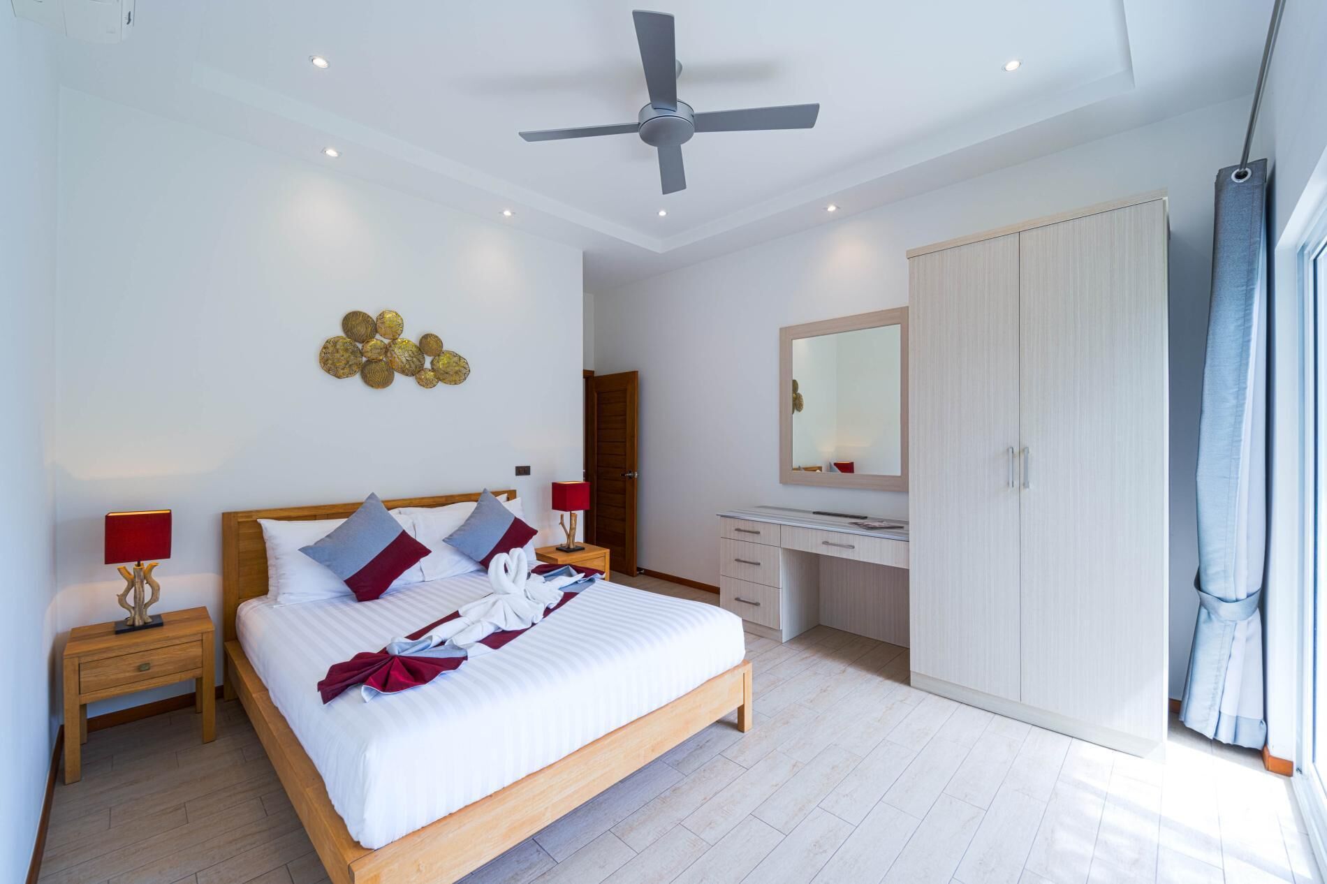A modern bedroom with a bed, bedside tables, a desk, and a wardrobe.