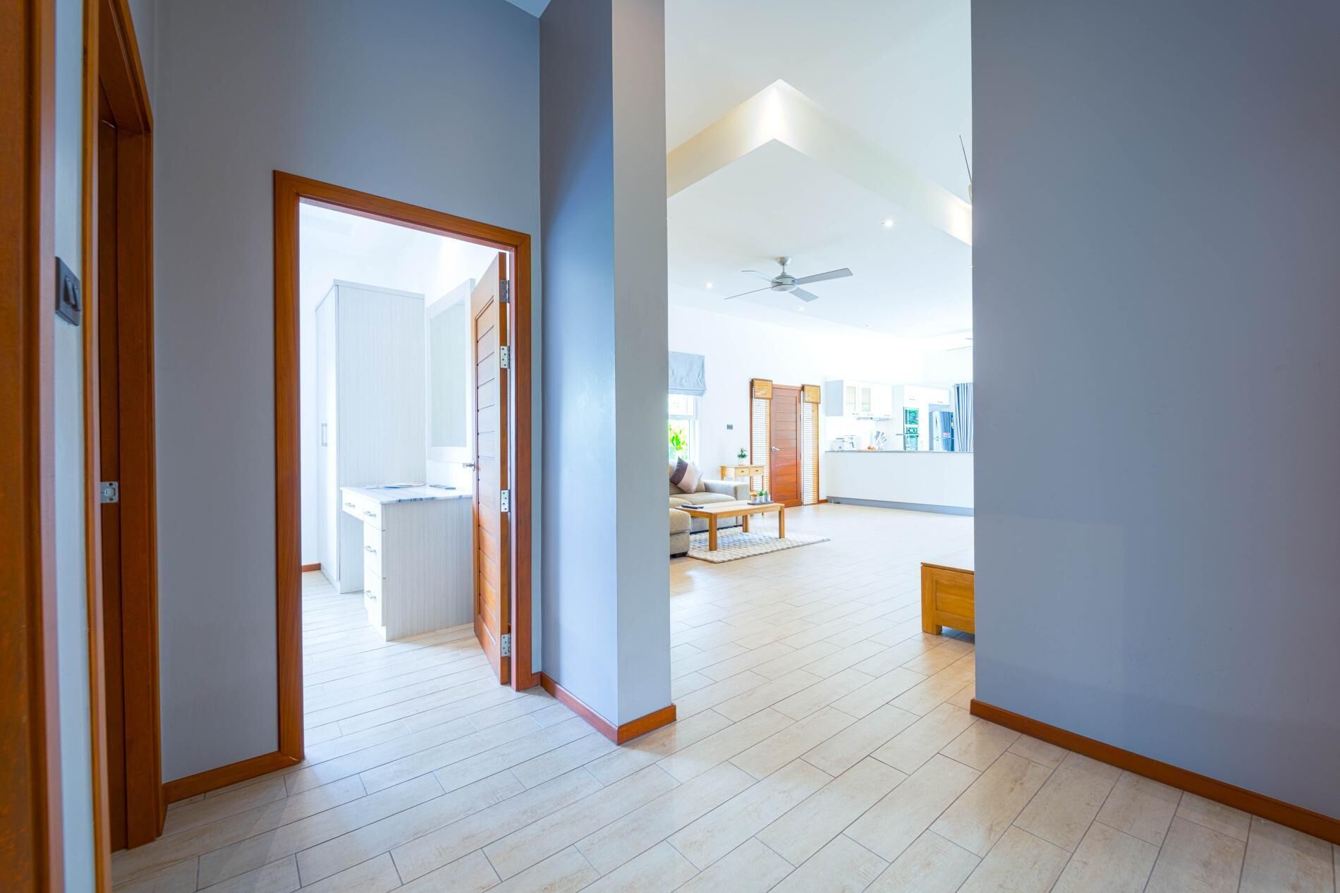 Un vaste espace de vie avec une cuisine à l’arrière-plan, un ventilateur de plafond et une vue sur l’extérieur.