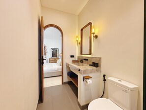 A modern bathroom with a toilet, sink, and mirror. - Villa Sylvia Canggu (Canggu)