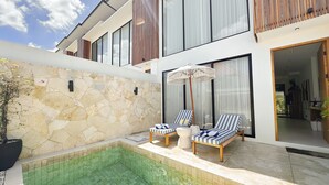 A modern house with a swimming pool, stone walls, and a balcony with lounge chairs. - Villa Sylvia Canggu (Canggu)