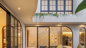 Een modern interieur met een houten terras, een zwembad en een eethoek met uitzicht op de keuken.