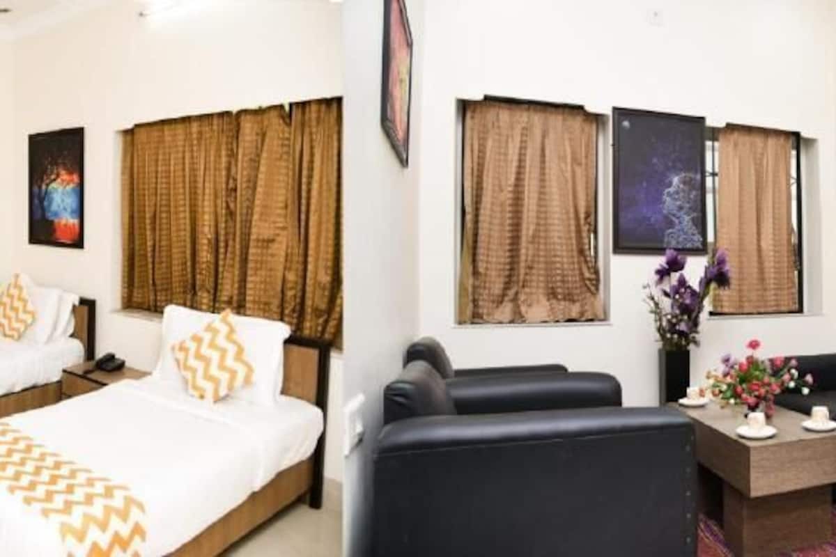 A hotel room with two beds, a sofa, a coffee table, and artwork on the walls.