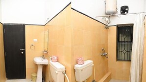 Une salle de bain avec deux toilettes, un lavabo et une douche.