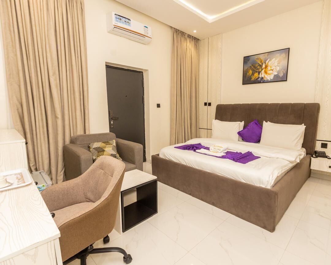 Una habitación de hotel con cama, escritorio, silla y puerta.