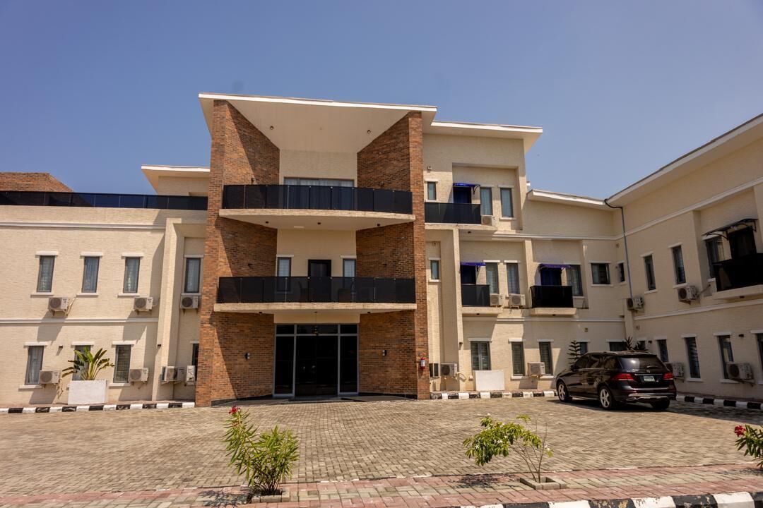 A multi-story building with a central entrance, balconies, and air conditioning units.