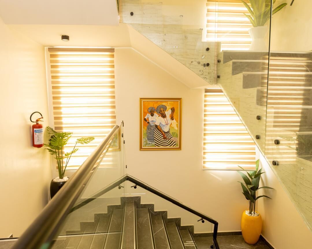 A staircase with glass railings, a fire extinguisher, and a framed artwork on the wall.