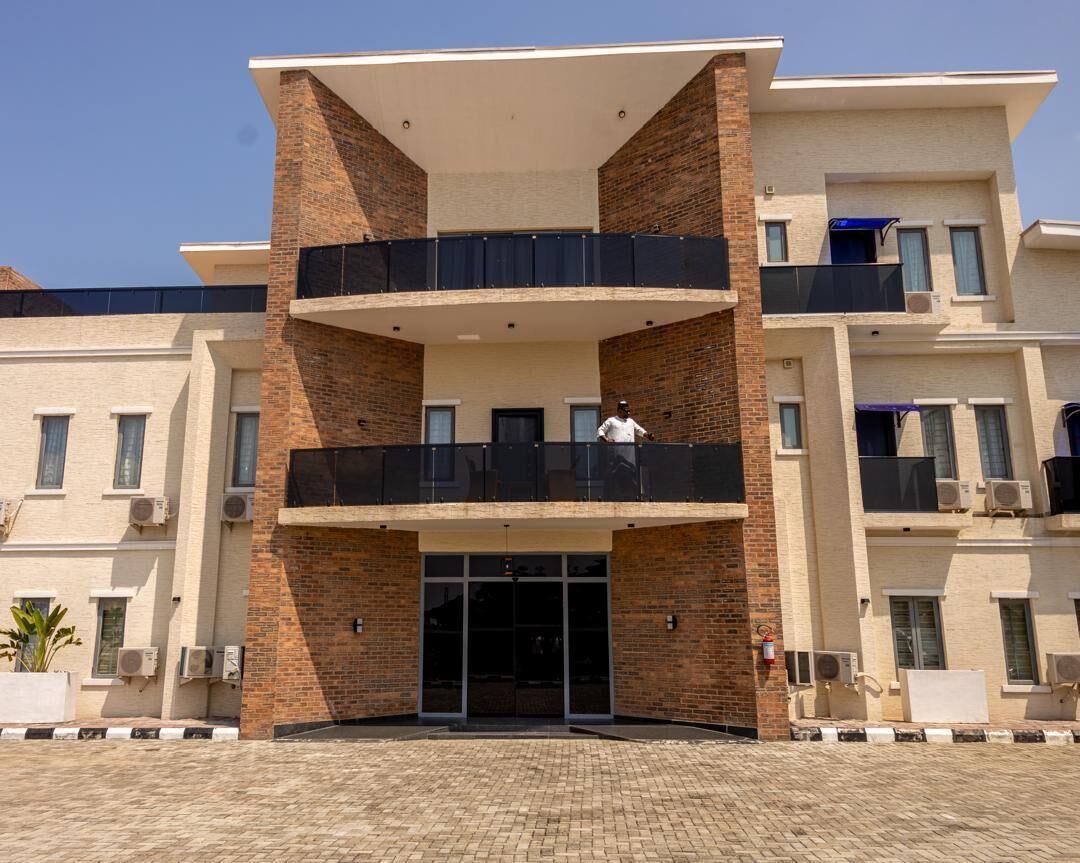 A multi-story building with a central entrance, balconies, and air conditioning units.