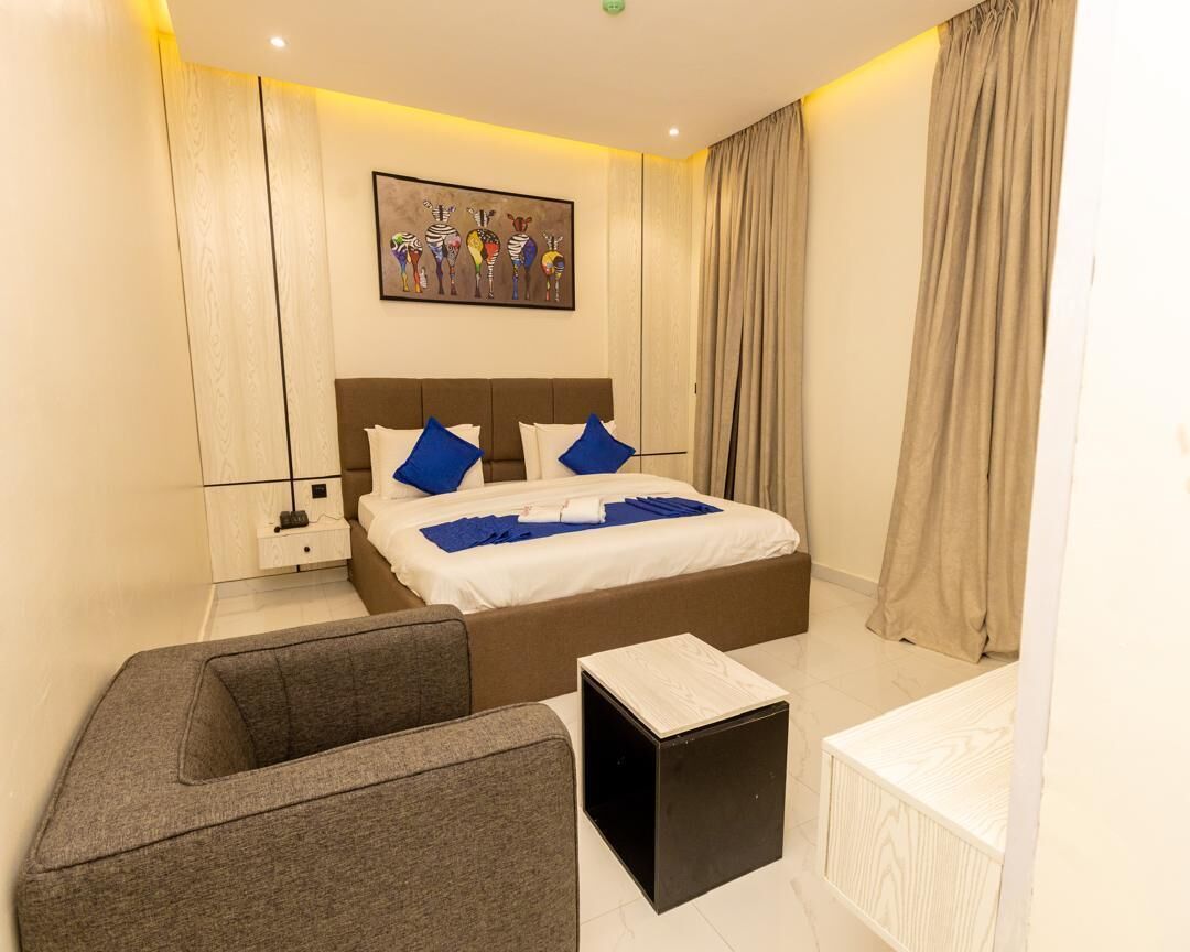 Une chambre d’hôtel moderne avec un grand lit, un petit canapé, une table de chevet et un tableau au mur.
