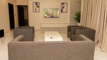 Uma sala de estar moderna com um sofá modular cinza, uma mesa de centro e uma TV de tela plana na parede.
