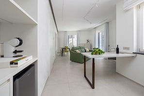 Ett modernt kök med en inbyggd diskmaskin, en matplats med en grön soffa och ett litet bord med en växt.