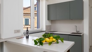 A modern kitchen with a white countertop, a built-in sink, and a window with a view of a building outside.