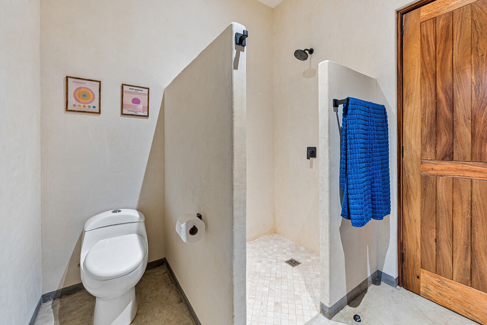 Un baño con inodoro, cabina de ducha y puerta de madera.