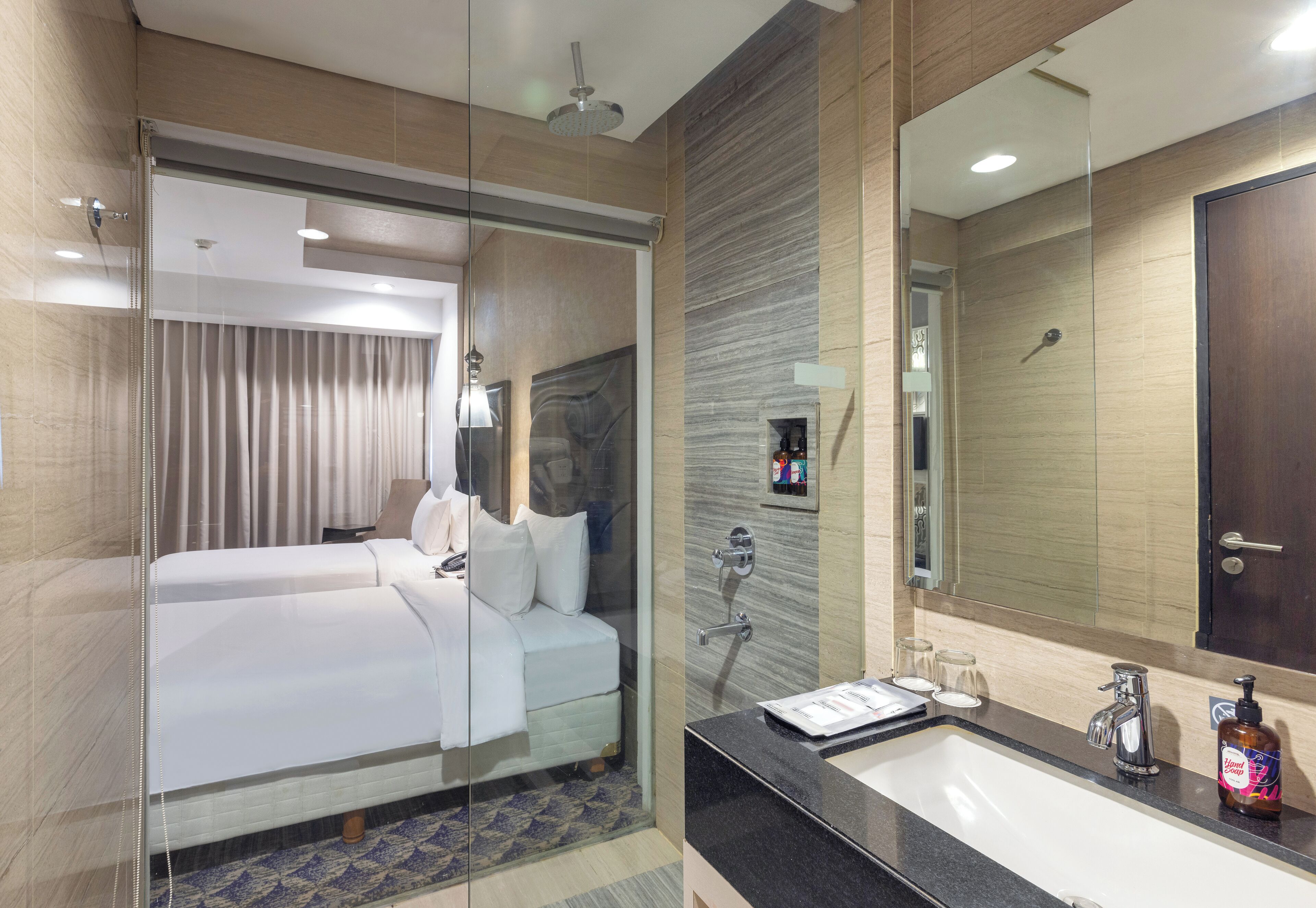 A hotel room with a bed, a bathroom with a sink and mirror, and a shower area.