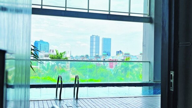 A room with a large window, a wooden deck, and a view of a cityscape. - Fairview Hotel by ARTOTEL (Jakarta)