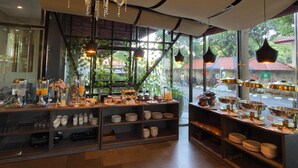 A café with a large chandelier, wooden shelves, and a variety of dishes and drinks displayed. - Fairview Hotel by ARTOTEL (Jakarta)