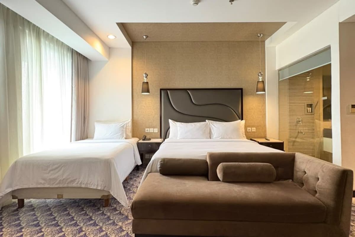 A hotel room with a large bed, a sofa, a desk, and a shower area.