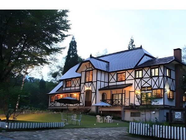 Un edificio de dos pisos con diseño Tudor, que presenta un techo empinado y estructura de madera expuesta.