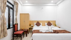 A hotel room with a bed, a desk, a chair, a wardrobe, and a window with curtains. - Hotel Kanak Kuteer (Ayodhya)