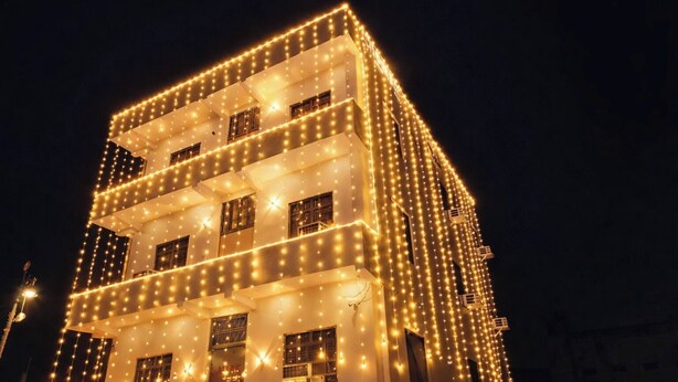 A multi-story building with a modern architectural design, featuring balconies and large windows. - Hotel Kanak Kuteer (Ayodhya)