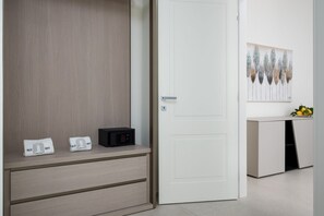 A modern room with a wardrobe, a bedside table with a radio, and a wall-mounted artwork.