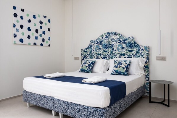 Una cama con cabecera estampada, una mesita de noche y una obra de arte en la pared.