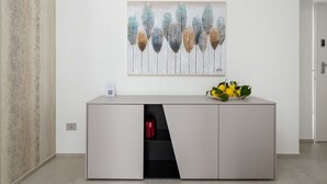 A modern interior with a white cabinet, a wall-mounted artwork, and a small plant on top.