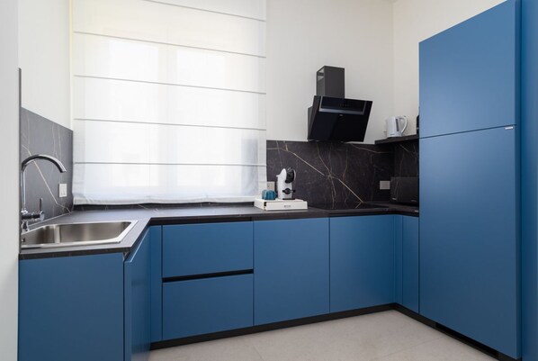 A modern kitchen with blue cabinets, a stainless steel sink, and a black countertop.