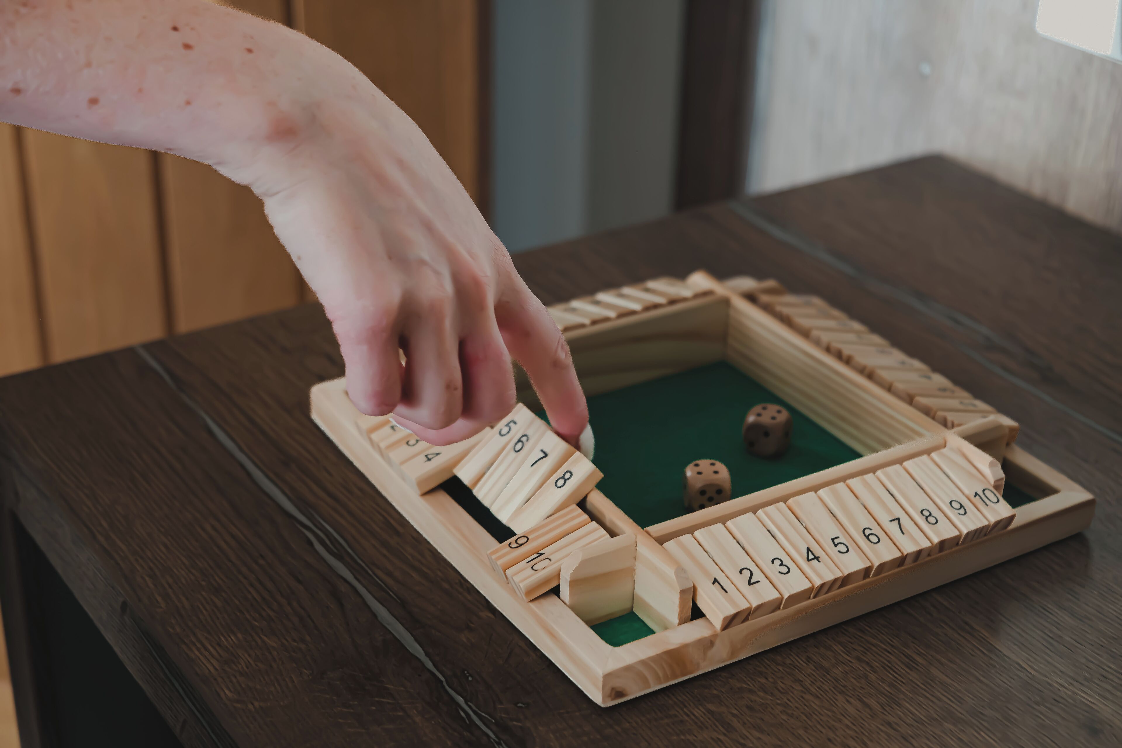 A wooden board game with numbered tiles on a dark wooden table.