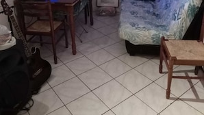 Un salon comprenant une table à manger, un canapé, un fauteuil, une guitare et un écran d’ordinateur.