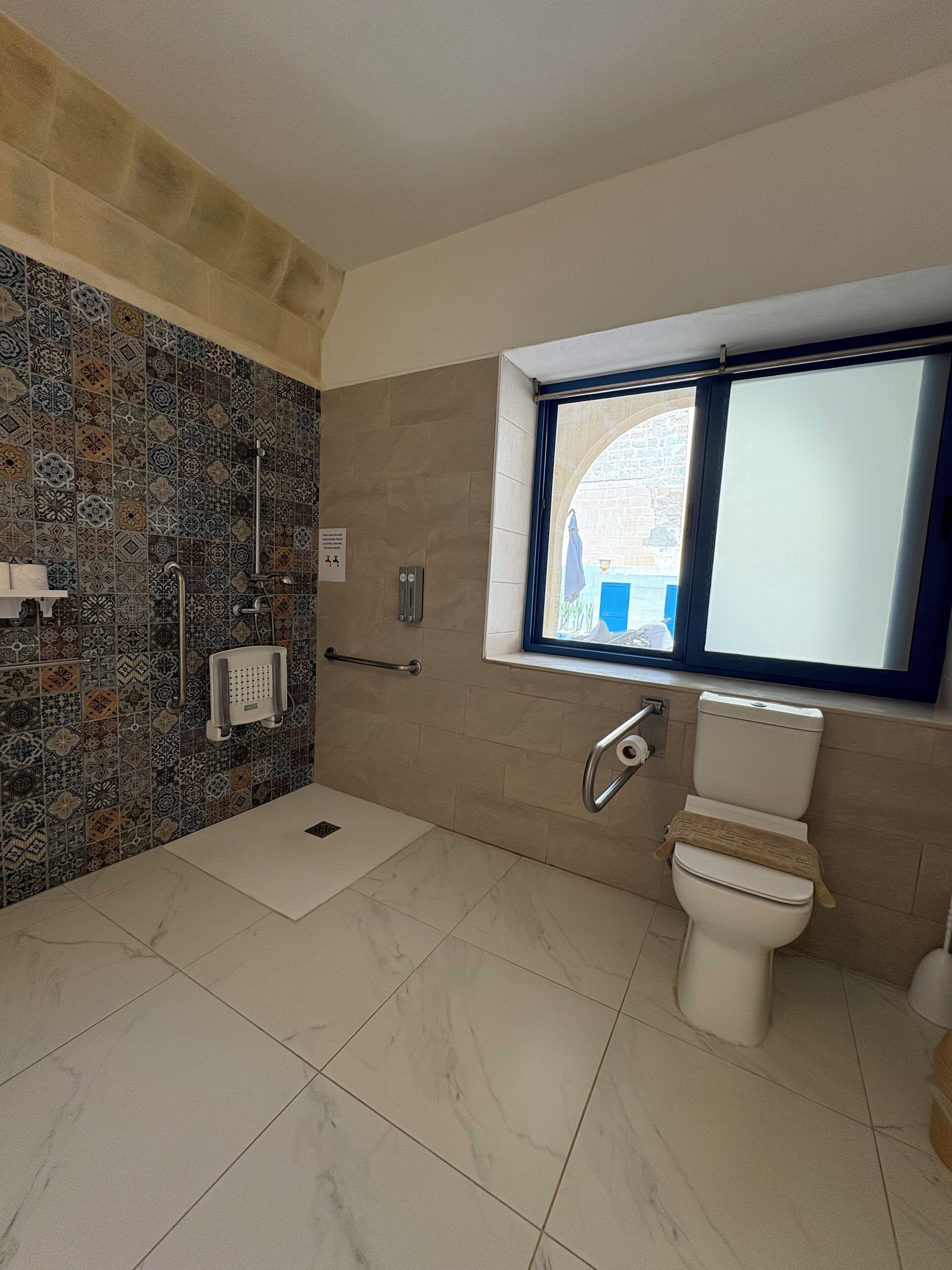 Une salle de bain avec une douche, des toilettes et une fenêtre.