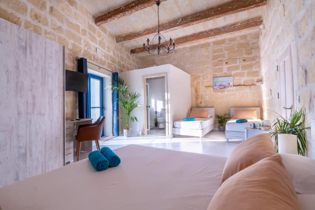 A bedroom with a large bed, a desk, a chair, and a nightstand.