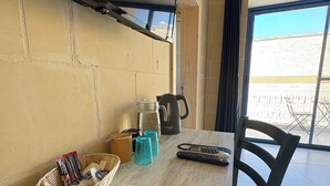 Una mesa con un menú, una cesta de revistas y un hervidor.