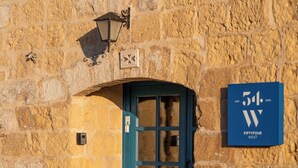Un edificio de piedra con puerta azul, una farola y un cartel que indica '54 West'.