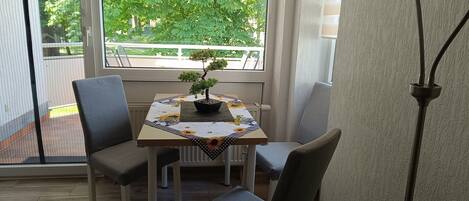 Een eetgedeelte met een tafel voor vier personen, een potplant en een lamp.