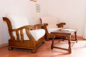 A room with two wooden armchairs with white cushions and a wooden table with a white cloth. - San Giuliano Two-room apartment 4 beds standard (Alghero)
