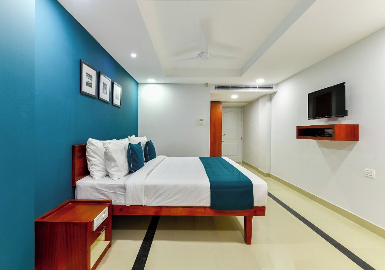 A modern hotel room with a bed, bedside table, and a mounted TV.