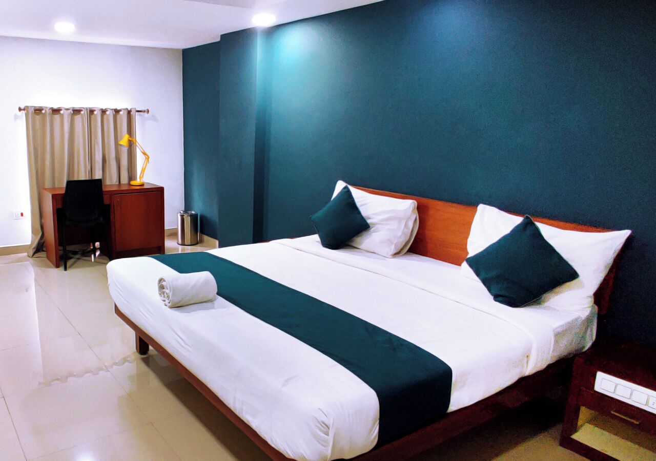 A hotel room with a large bed, a desk, and a chair.