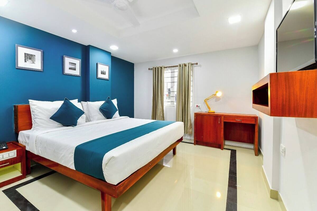 A modern hotel room with a large bed, a desk, and a TV.