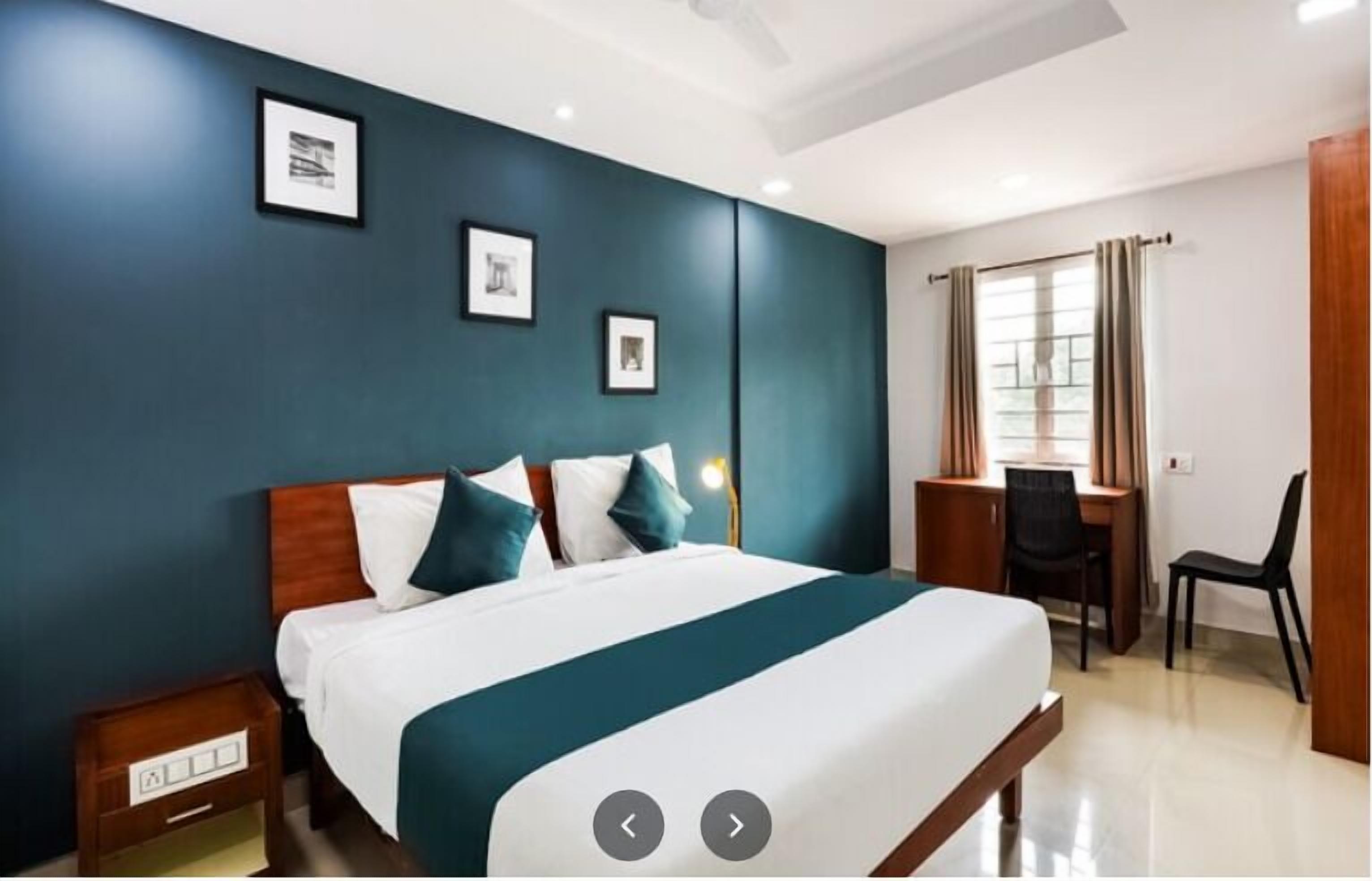 A modern hotel room with a large bed, a desk, and a chair.