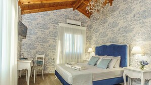 A bedroom with a bed, a chair, a desk, a lamp, and a chandelier. - Villa Simantiri - Romantic Luxury Villa with jacuzzi & sunset views (Pompia)
