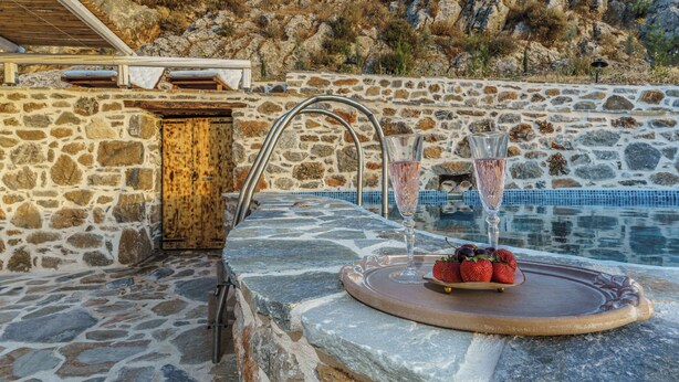 A stone pool with a wooden deck, a glass of champagne, and strawberries on a tray. - Villa Simantiri - Romantic Luxury Villa with jacuzzi & sunset views (Pompia)
