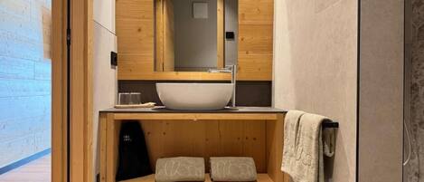 A modern bathroom with a wooden vanity, a large sink, and a towel rack.