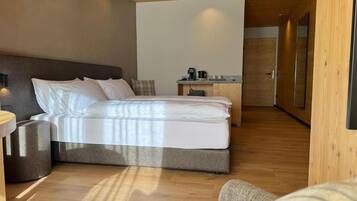 Una camera d'hotel moderna con un letto grande, una scrivania piccola e un angolo cottura.